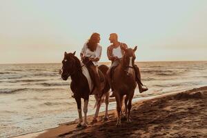 um casal apaixonado em roupas de verão, montando um cavalo em uma praia ao pôr do sol. mar e pôr do sol ao fundo. foco seletivo foto