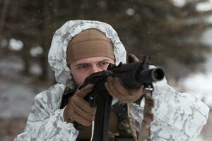 guerra de inverno nas montanhas árticas. operação em condições frias. soldado no uniforme camuflado de inverno no exército de guerra moderna em um dia de neve no campo de batalha da floresta com um rifle. foco seletivo foto