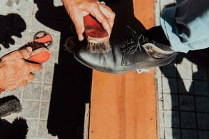 a velho homem mão polimento e pintura uma Preto sapato às rua foto