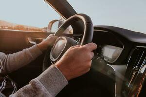 fechar acima homem mão dirigindo uma carro às pôr do sol. a conceito do carro viagem foto