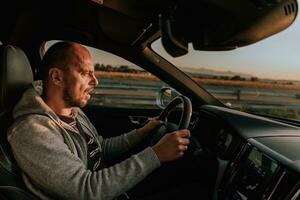 uma homem com uma oculos de sol dirigindo uma carro às pôr do sol. a conceito do carro viagem foto