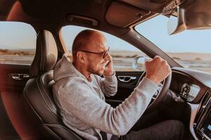 a motorista recebe feliz em formação enquanto falando em a Smartphone enquanto dirigindo a carro foto
