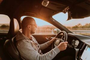 uma homem com uma oculos de sol dirigindo uma carro às pôr do sol. a conceito do carro viagem foto