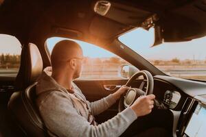 uma homem com uma oculos de sol dirigindo uma carro às pôr do sol. a conceito do carro viagem foto