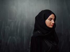 retrato do lindo muçulmano mulher dentro elegante vestir com hijab dentro frente do Preto quadro-negro representando moderno islamismo moda e Ramadã kareem conceito foto