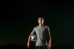 retrato do uma jovem bonito futebol jogador homem em uma rua jogando com uma futebol bola. foto