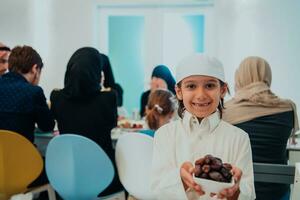 eid Mubarak muçulmano família tendo iftar jantar pequeno Garoto segurando uma prato cheio do doce datas para pausa celebração. comendo tradicional Comida durante Ramadã festa mês às lar. a islâmico halal comendo foto