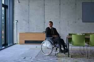 homem de negocios dentro uma cadeira de rodas dentro uma moderno escritório solitário depois de uma ocupado dia foto