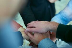 uma topo Visão foto do grupo do empresários segurando mãos juntos para simbolizar unidade e força
