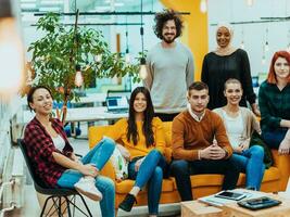 grupo do multiétnico colegas trabalhando em Área de Trabalho computadores, computador portátil e partilha seus Ideias dentro uma moderno escritório espaço.jovem influenciadores trabalhos em conectados marketing projetos. foto