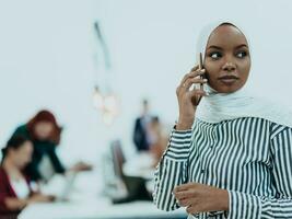 jovem africano americano empresária falando em uma Smartphone dentro uma moderno comece escritório. marketing conceito. multiétnico sociedade. foto