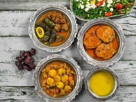 eid Mubarak tradicional Ramadã iftar jantar. sortido saboroso Comida dentro autêntico rústico pratos em de madeira azul fundo. turco bósnio Comida carne Churrasquinho, Pão Pita, sarma, klepe, sogan dolma. foto