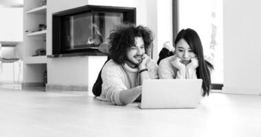 jovem casal multiétnico usando um laptop no chão foto