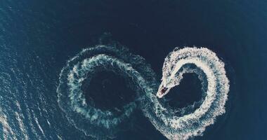 aéreo topo Visão do uma branco prazer barco em uma verão dia. barco a motor virar ciclo oito em a mar fazer metaverso infinidade futuro conceito. foto