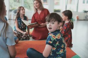 lendo Tempo dentro a elementar escola ou Jardim da infância, uma professor lê uma livro para crianças dentro a elementar escola ou Jardim da infância. a conceito do pré escola Educação. seletivo foco foto