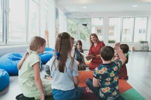 lendo Tempo dentro a elementar escola ou Jardim da infância, uma professor lê uma livro para crianças dentro a elementar escola ou Jardim da infância. a conceito do pré escola Educação. seletivo foco foto