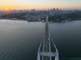 Istambul bósforo ponte e cidade Horizonte dentro fundo com turco bandeira às lindo pôr do sol, aéreo deslizar órbita e rastreamento tiro foto