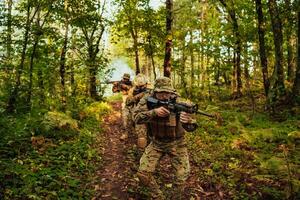 uma grupo do moderno guerra soldados é brigando uma guerra dentro perigoso controlo remoto floresta áreas. uma grupo do soldados é brigando em a inimigo linha com moderno armas. a conceito do guerra e militares conflitos foto