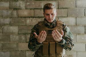 uma muçulmano soldado do a especial forças ora para Deus de levantando dele mãos e começa uma oração foto