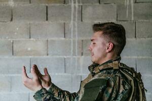 uma muçulmano soldado do a especial forças ora para Deus de levantando dele mãos e começa uma oração foto