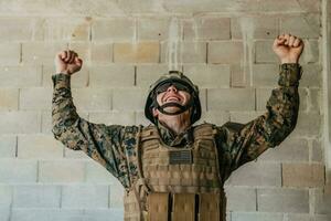 sucesso dentro a guerra campanha. uma soldado com elevado mãos comemora a bem sucedido conquista do inimigo território foto