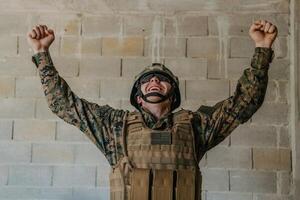 sucesso dentro a guerra campanha. uma soldado com elevado mãos comemora a bem sucedido conquista do inimigo território foto