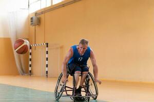 veteranos de guerra com deficiência em ação enquanto jogavam basquete em uma quadra de basquete com equipamentos esportivos profissionais para deficientes foto