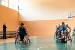 Veteranos de guerra com deficiência equipes de basquete de raça mista e idade em cadeiras de rodas jogando uma partida de treinamento em um ginásio de esportes. conceito de reabilitação e inclusão de pessoas com deficiência foto