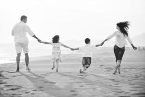 família jovem feliz se diverte na praia ao pôr do sol foto