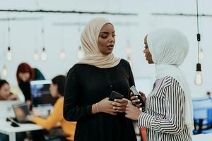 retrato do dois africano americano mulheres de negócios falando para cada de outros enquanto em pé dentro uma moderno o negócio escritório com seus colegas. marketing conceito. multiétnico sociedade. foto