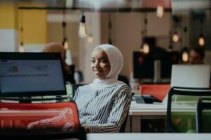 o negócio Educação e escritório conceito. africano americano empresária vestindo uma hijab trabalhando, digitando em uma computador. fêmea empreendedor sentado em dela escrivaninha. foto