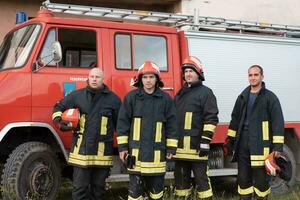 grupo do fogo lutadores em pé confiante depois de uma bem feito resgate Operação. bombeiros pronto para emergência serviço. foto