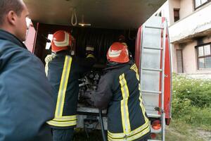 grupo do fogo lutadores em pé confiante depois de uma bem feito resgate Operação. bombeiros pronto para emergência serviço. foto