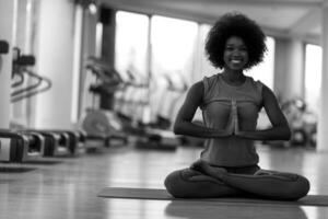 mulher afro-americana exercita ioga no ginásio foto