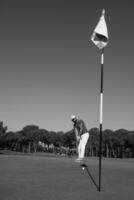 jogador de golfe acertando tiro em dia ensolarado foto