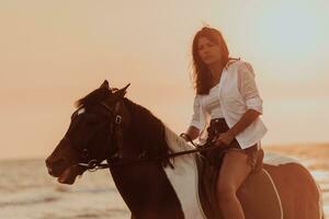 mulher com roupas de verão gosta de andar a cavalo em uma bela praia ao pôr do sol. foco seletivo foto