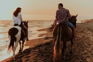 um casal apaixonado em roupas de verão, montando um cavalo em uma praia ao pôr do sol. mar e pôr do sol ao fundo. foco seletivo foto