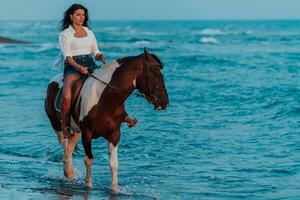 mulher com roupas de verão gosta de andar a cavalo em uma bela praia ao pôr do sol. foco seletivo foto