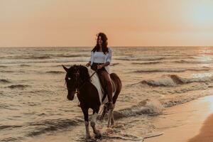 mulher com roupas de verão gosta de andar a cavalo em uma bela praia ao pôr do sol. foco seletivo foto