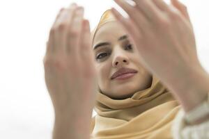retrato do lindo muçulmano mulher dentro elegante vestir com hijab fazer tradicional oração para Deus mantém mãos dentro Rezar gesto isolado em branco fundo foto