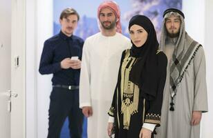 grupo retrato do jovem muçulmano pessoas mulheres dentro elegante hijab vestir com três árabe homens usando smartphones às moderno brilhante casa foto