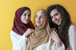 grupo retrato do lindo muçulmano mulheres dois do eles dentro uma elegante vestir com hijab isolado em uma amarelo fundo foto