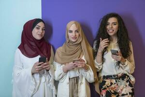 grupo retrato do lindo muçulmano mulheres dois do eles dentro uma elegante vestir com hijab isolado em uma colorida fundo foto