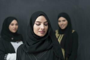 grupo retrato do lindo muçulmano mulheres dentro uma elegante vestir com hijab isolado em Preto fundo foto