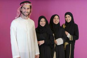 grupo retrato do jovem muçulmano pessoas árabe homens com três muçulmano mulheres dentro uma elegante vestir com hijab isolado em uma Rosa fundo foto