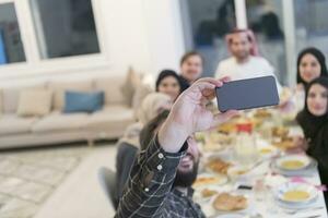 eid Mubarak muçulmano família tendo iftar jantar levando As fotos com Móvel telefone enquanto comendo tradicional Comida durante Ramadã festa mês às lar. a islâmico halal comendo e bebendo islâmico famil