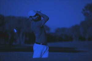 golfista profissional acertando um tiro de bunker de areia foto