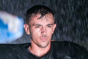 americano futebol campo solitário atleta Guerreiro em pé em uma campo detém dele capacete e pronto para jogar. jogador preparando para correr, ataque e Ponto aterragem. chuvoso noite com dramático névoa, azul luz foto