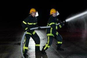 bombeiros usar uma água mangueira para eliminar uma fogo perigo. equipe do bombeiros dentro a perigoso resgate missão. foto