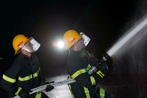 bombeiros usar uma água mangueira para eliminar uma fogo perigo. equipe do bombeiros dentro a perigoso resgate missão. foto